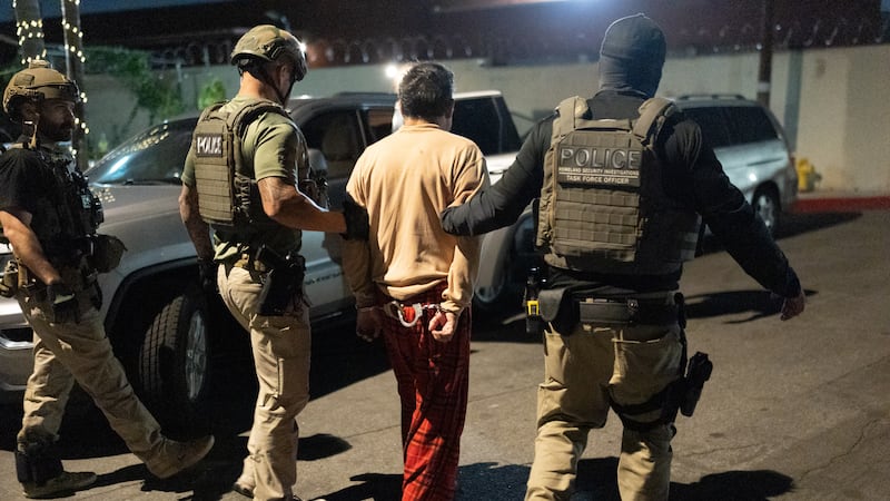Homeland Security Investigations task force officers escort a suspect accused of illegally...
