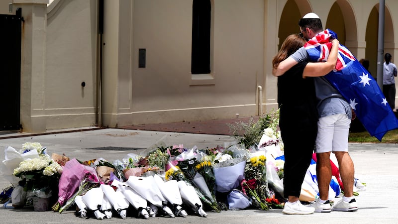 A couple lay flowers at a tribute to shooting victims outside the Bondi Pavilion at Sydney's...