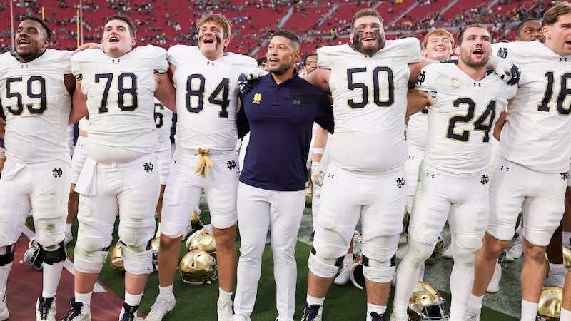Notre Dame head coach Marcus Freeman, center, chants with his players after the team's win...