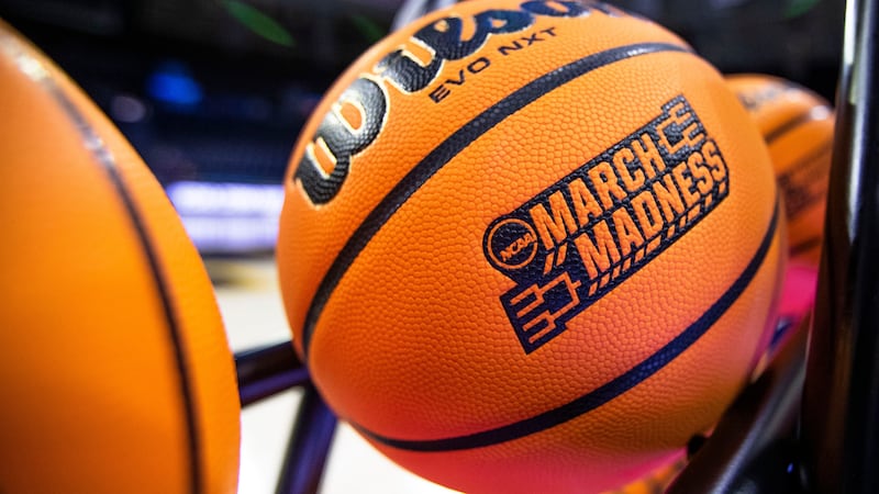 FILE - A basketball with a March Madness logo rests on a rack before a First Four game between...